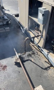 A rooftop HVAC unit undergoing service with steam visible at Schomp's Mechanical Services in Brookings, SD.