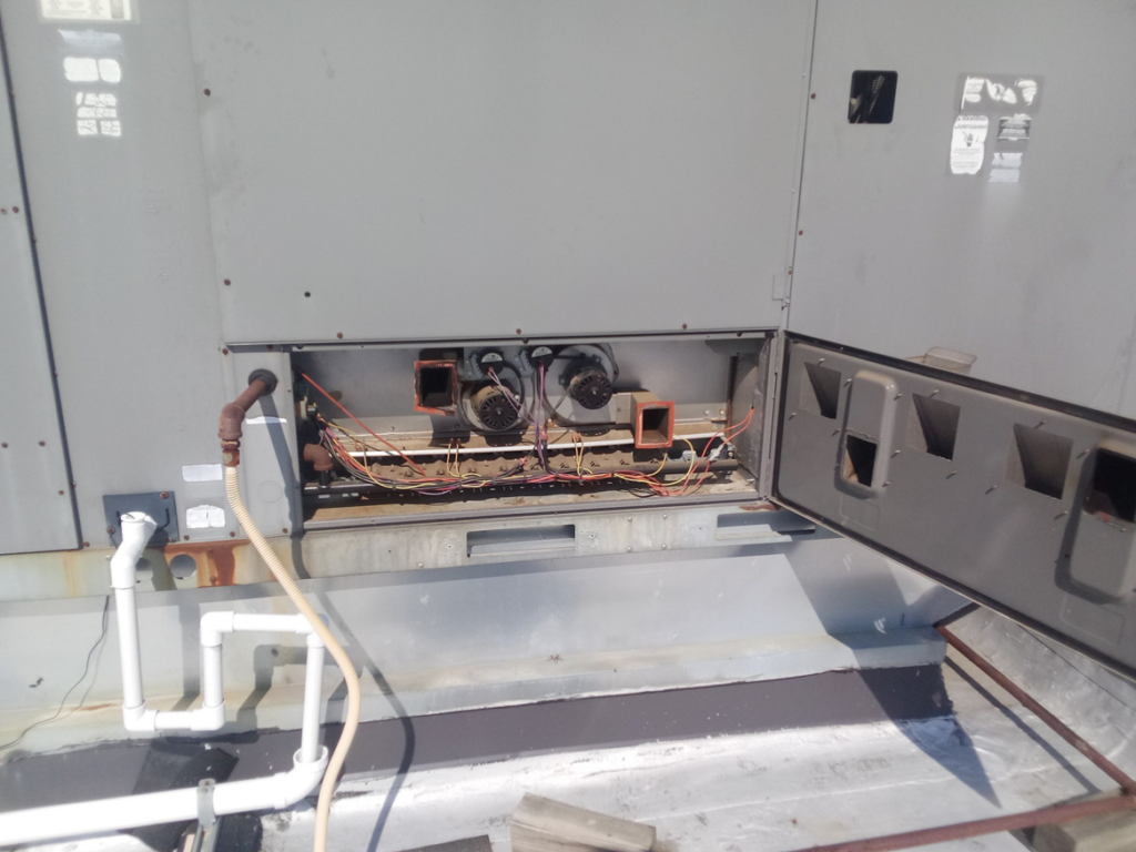 A rooftop HVAC unit with an open panel showing internal components, indicating service by TAG Heat N Air in North Little Rock, AR.