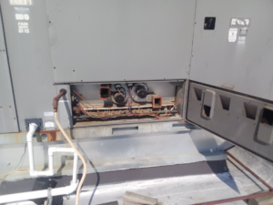 A rooftop HVAC unit with an open panel showing internal components, indicating service by TAG Heat N Air in North Little Rock, AR.