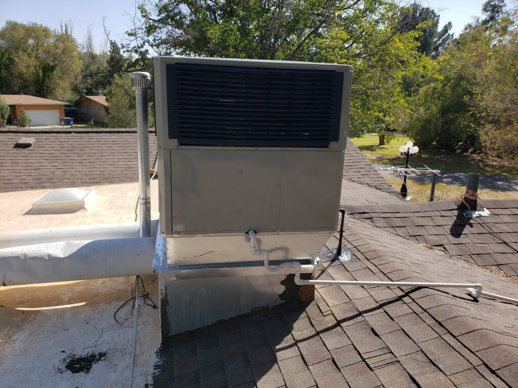 A rooftop HVAC unit with ductwork installed on a shingle roof by Dynamic Heating, Cooling, Refrigeration & Roofing in El Paso, TX.