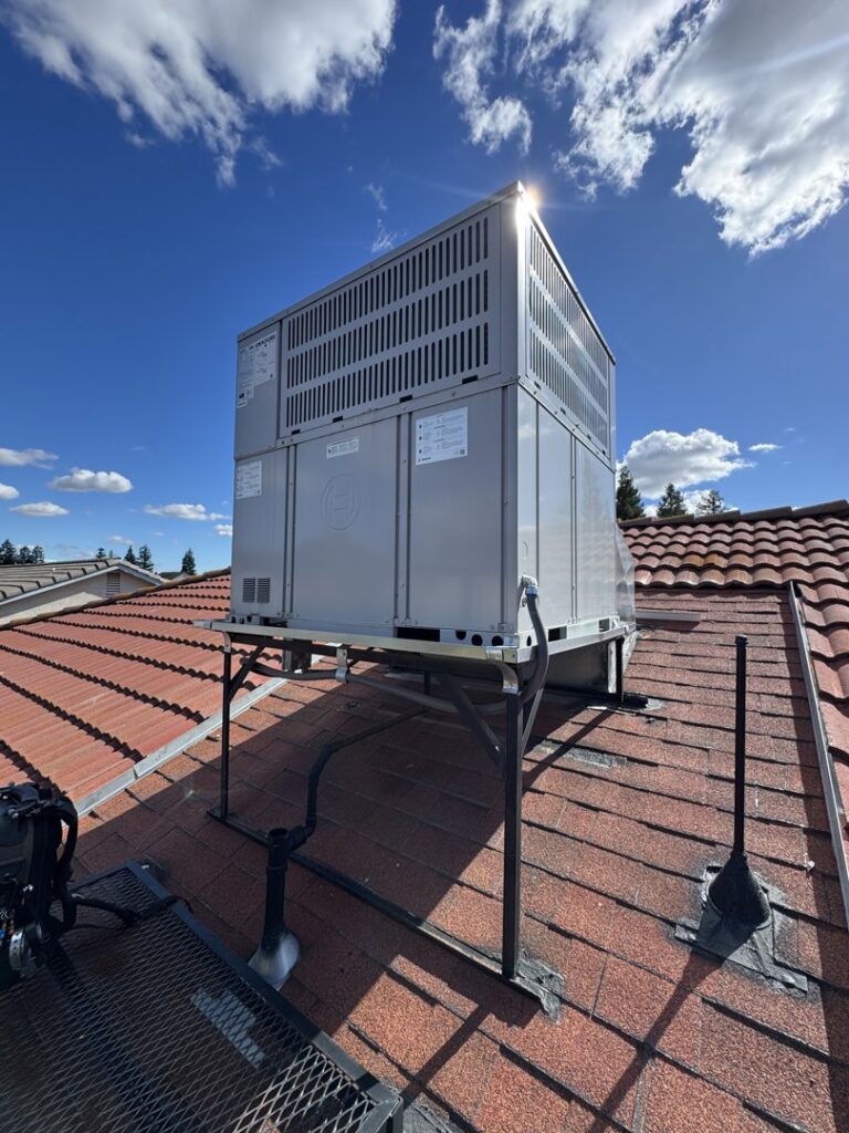 An outdoor rooftop HVAC unit on a red tile roof under a sunny sky by Just Chillin' Heating & Air Conditioning, Inc. in Fresno, CA.