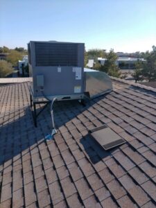 A rooftop HVAC unit with new ductwork installed on a shingled roof by Desert Heroes HVAC in Phoenix, AZ