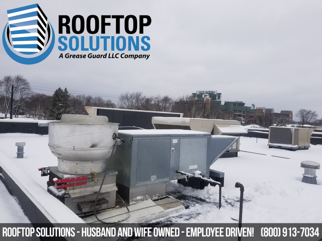 Rooftop HVAC units covered in snow, showcasing commercial equipment serviced by Grease Guard, LLC in Naperville, IL