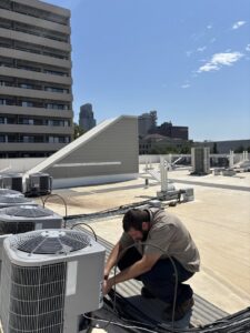 An HVAC technician performing maintenance on multiple rooftop HVAC units for Polar Air Heating and Cooling in Omaha, NE
