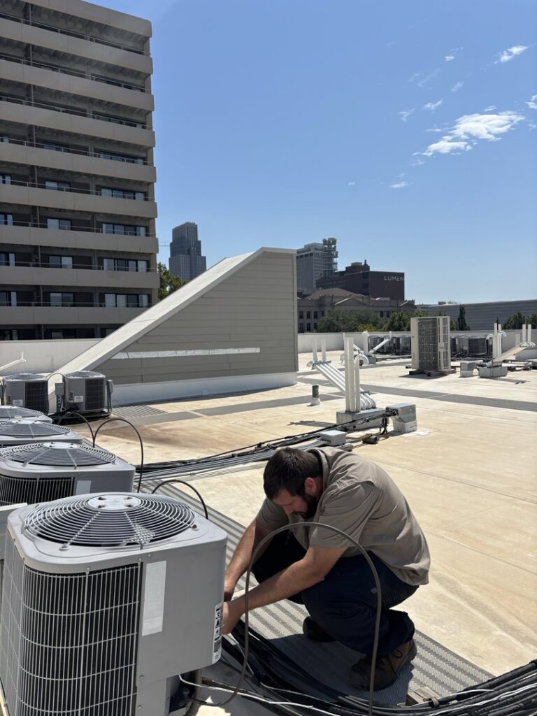 An HVAC technician performing maintenance on multiple rooftop HVAC units for Polar Air Heating and Cooling in Omaha, NE