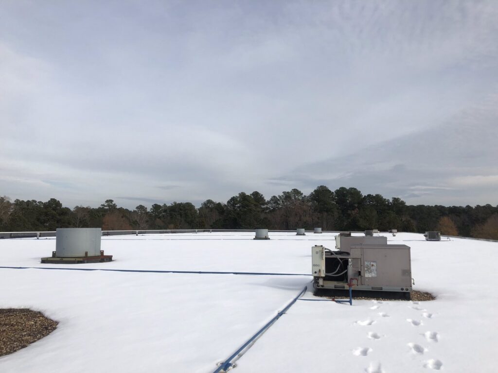 Rooftop HVAC units on a snowy day, maintained by Raleigh Comfort Services in Raleigh, NC.