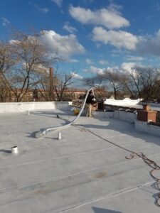 A technician on a rooftop installing ventilation ductwork for HVAC Royal Service Inc in Chicago, IL.