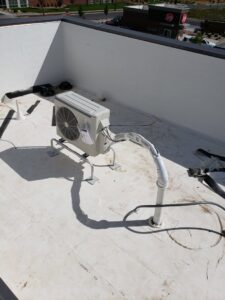 A mini-split air conditioning condenser unit installed on a rooftop by ABT Heating and Cooling in Orem, UT.