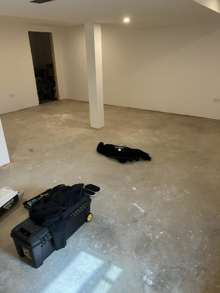 A large room with concrete floor and tack strips installed, ready for carpet installation by Creative Carpet Solutions LLC in Houston, TX.