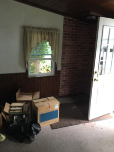 A room with dirty carpet and moving boxes, suggesting a carpet cleaning or removal service by A Little More Martha, LLC in Lansing, MI.