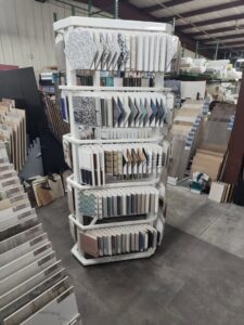 A rotating display stand showcasing various tile samples at CarpetsPlus Colortile in Swansea, MA