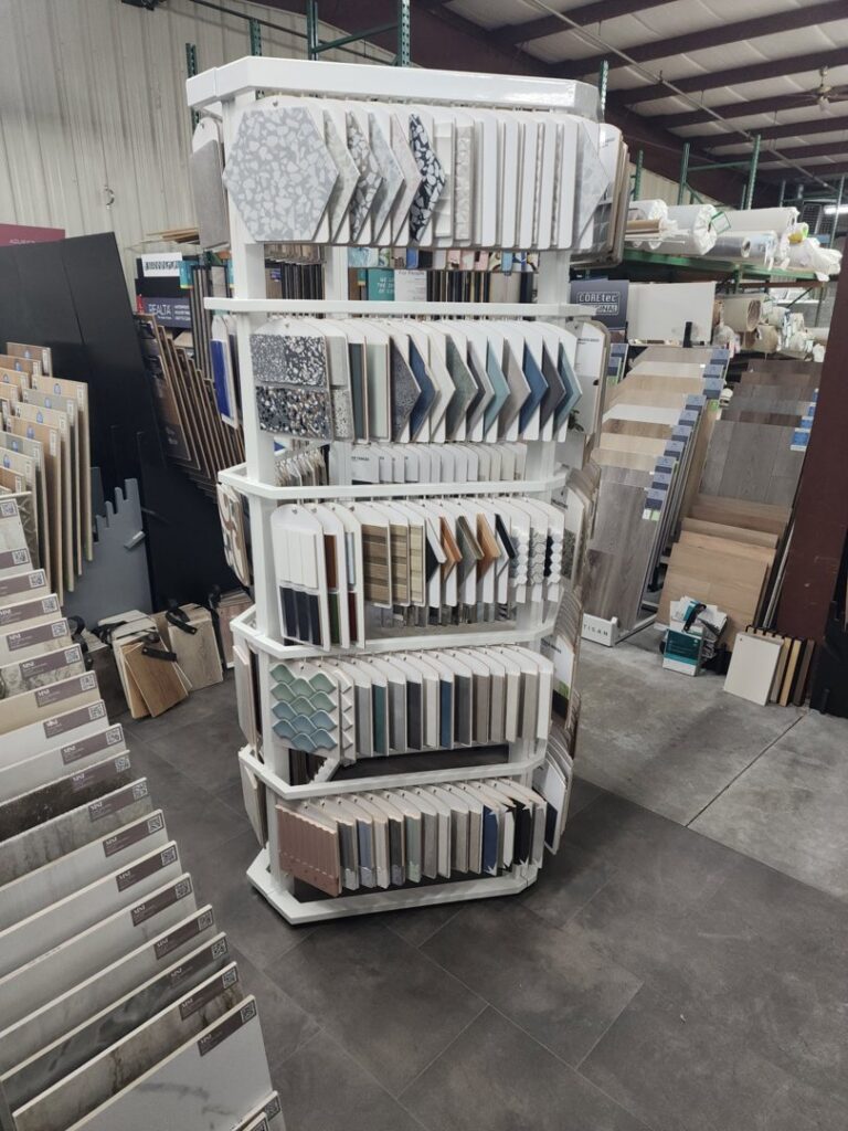 A rotating display stand showcasing various tile samples at CarpetsPlus Colortile in Swansea, MA