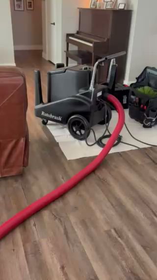 A Rotobrush duct cleaning machine with its red hose laid out on a wooden floor by Duct Dudes in Scottsdale, AZ.