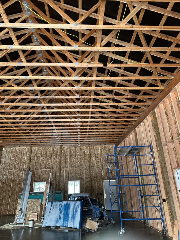 Rough-in electrical wiring visible along wooden trusses in a garage or workshop under construction by Sunrise Electric LLC in Kalispell, MT.