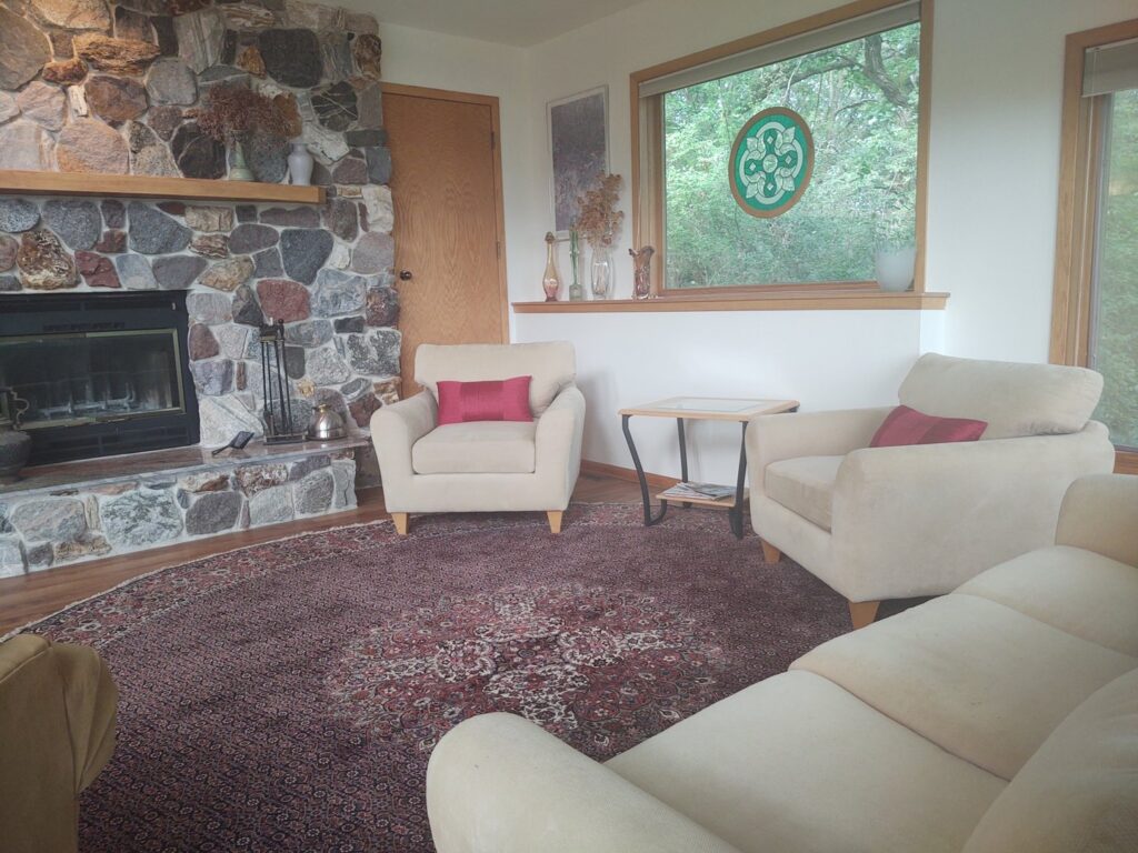 A beautiful round oriental rug anchoring a cozy living room with a stone fireplace, installed by Borokhim's Oriental Rugs in Madison, WI.