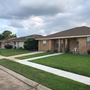 A row of residential houses featuring well-maintained lawns, showcasing the work of Mcfaith Lawn Care LLC in New Orleans, LA.