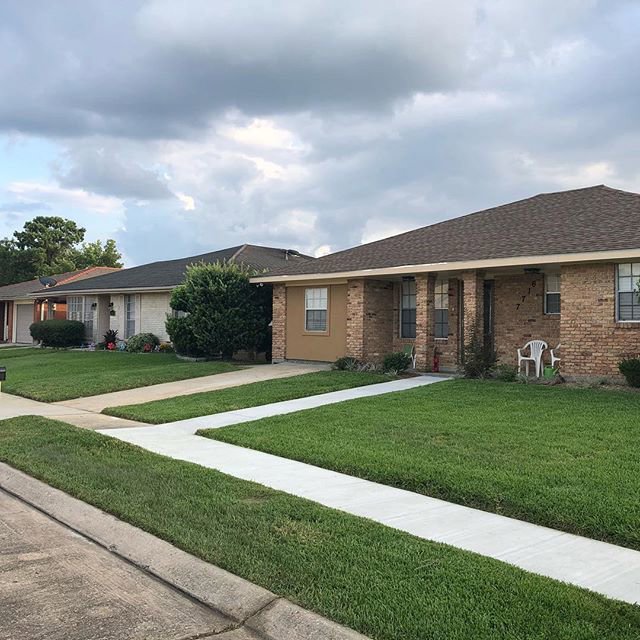 A row of residential houses featuring well-maintained lawns, showcasing the work of Mcfaith Lawn Care LLC in New Orleans, LA.