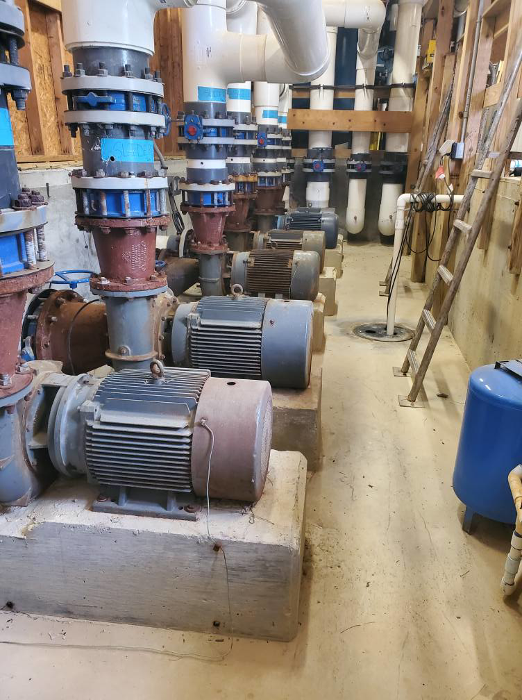A row of industrial electric motors and pumps, typical equipment serviced by Caddell Electric Co Inc in Dallas, TX.