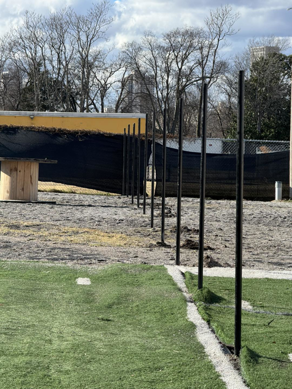 A row of newly installed fence posts on an artificial turf field by Just Handy Fence and Stain LLC in Tulsa, OK.