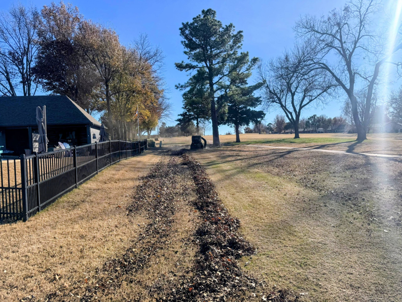 Neatly raked rows of autumn leaves on a residential lawn, ready for removal by Redline Mowing & Trimming in Stillwater, OK.