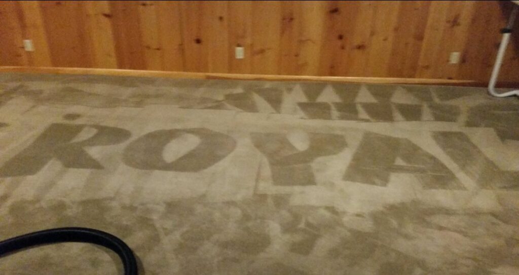 The word "ROYAL" visibly cleaned into a carpet, showcasing the work of Royal Carpet & Upholstery Cleaning in Lincoln, NE.
