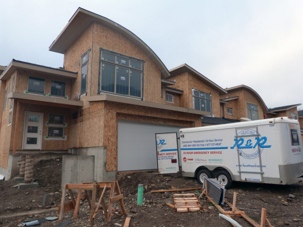 An R&R Heating & Air Conditioning service trailer parked at a new home construction site in Spokane, WA.