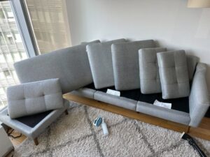 Cleaning equipment and a disassembled sofa on a rug, indicating a rug and upholstery cleaning job by BeClean in Charlotte, NC.