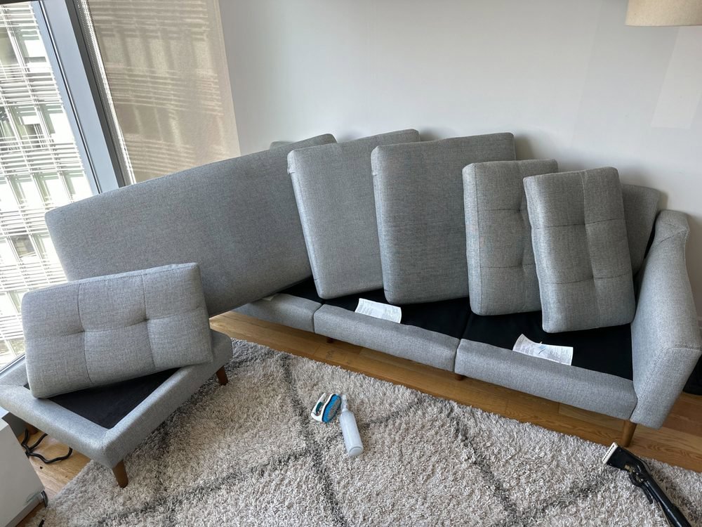 Cleaning equipment and a disassembled sofa on a rug, indicating a rug and upholstery cleaning job by BeClean in Charlotte, NC.