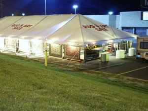 An outdoor tent displaying rugs and art for sale by Sunshine Rugs and Art in Londonderry, NH.