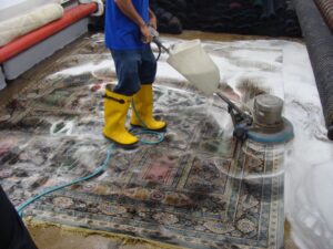 A close-up view of a rug's backing showing a stain, laid over another patterned carpet at Dave's Magikist, Inc. in Milwaukee, WI.