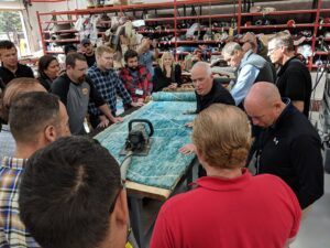 A professional demonstrating rug care techniques with a tool to a group at the Association of Rug Care Specialists in Salem, OR