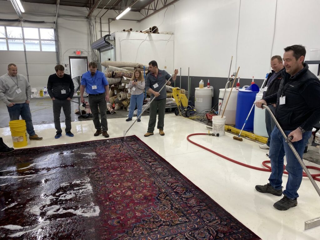 Professionals demonstrating rug cleaning techniques at the Association of Rug Care Specialists in Salem, OR