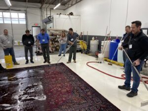 Professionals demonstrating rug cleaning techniques at the Association of Rug Care Specialists in Salem, OR