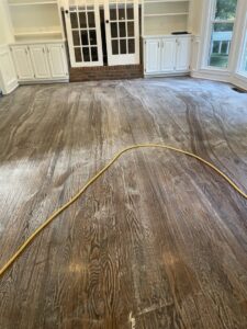 A professional cleaning a rug with a carpet wand, showing a clear before-and-after line, by Atlanta Top Force Carpet Cleaning in Roswell, GA.