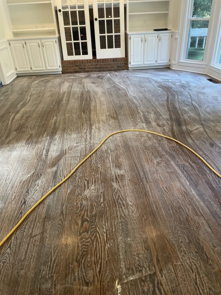 A professional cleaning a rug with a carpet wand, showing a clear before-and-after line, by Atlanta Top Force Carpet Cleaning in Roswell, GA.