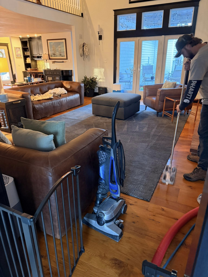 A technician cleaning a dark area rug in a living room at First Response Custom Cleaning in Newport News, VA