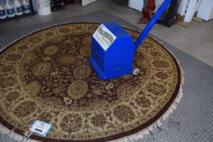 A professional rug duster machine operating on a large oriental rug at Oriental Rug Cleaning Facility in Tampa, FL