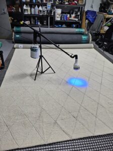 A large area rug undergoing inspection with a UV light, possibly for stains or pet odors, at Personal Touch Carpet Cleaning in Chicago, IL.
