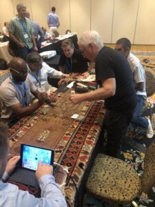 A professional demonstrating rug repair techniques on a table to a group at the Association of Rug Care Specialists in Salem, OR
