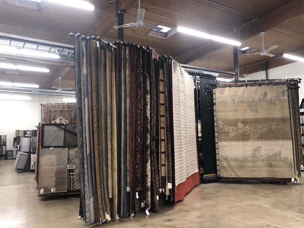 Interior view of the rug showroom with many rugs on display at Artifacts Fine Rugs and Flooring in South Salt Lake, UT.