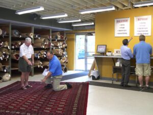 The interior of the rug store with rolled rugs on shelves and a person at the counter at American Rug Laundry in Saint Paul, MN.