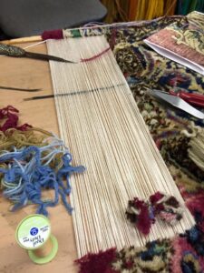 Close-up of a rug weaving and repair loom with threads and yarn at Mussallem Area Rug Specialist in Jacksonville, FL.