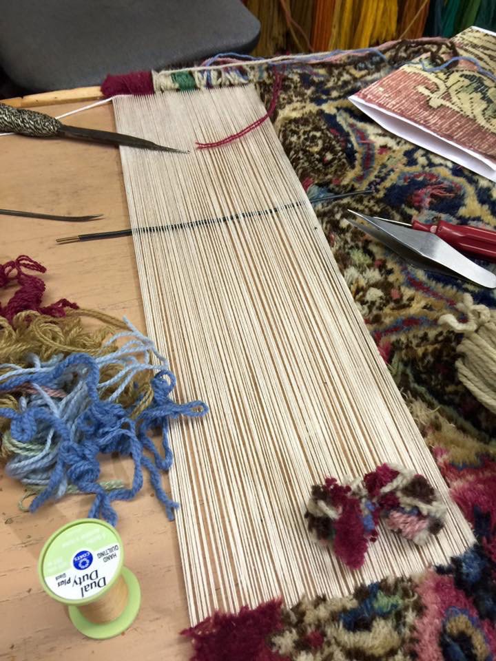 Close-up of a rug weaving and repair loom with threads and yarn at Mussallem Area Rug Specialist in Jacksonville, FL.