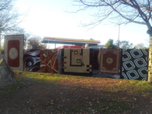 Various patterned rugs displayed outdoors for sale by Sunshine Rugs and Art in Londonderry, NH.