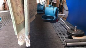 Multiple rugs hanging to dry with industrial air movers in the Rug Renew facility in Spring Valley, CA.