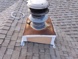 A rusted and damaged chimney cap and flashing on a residential roof, indicating a need for repair by A Step Above Chimney & Siding in Wichita, KS.