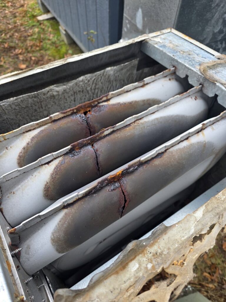 A close-up view of a rusted and cracked furnace heat exchanger, indicating a need for repair by Sizemore Heating & Air, LLC in Chapel Hill, NC