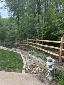 A rustic split rail fence installed in a wooded area by Sexton Property Services STL in High Ridge, MO.