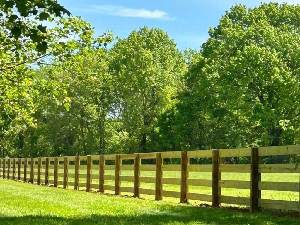 A rustic wood rail fence installed in a green field by Frontier Fence LLC Bowling Green,Ky