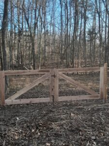 A rustic wood gate with wire mesh, suitable for a rural or wooded property, installed by Aguilarfence services LLC in Clayton, NC.